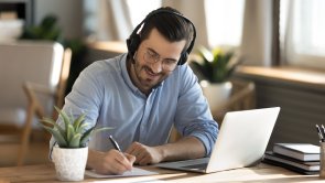 Smiling Caucasian man in headphones study on laptop Smiling Caucasian man in headphones study on laptop